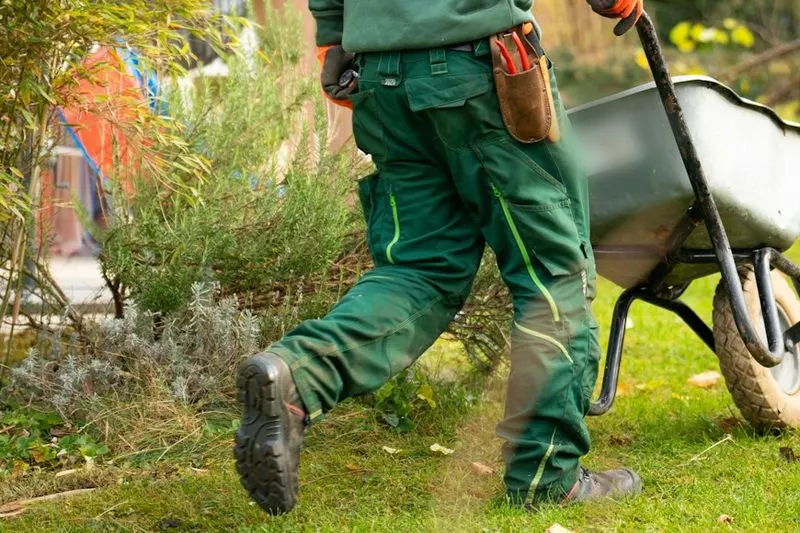 Landschaftsgärtner schiebt eine Schubkarre über den Rasen, Website für Garten- und Landschaftsbau in Köln